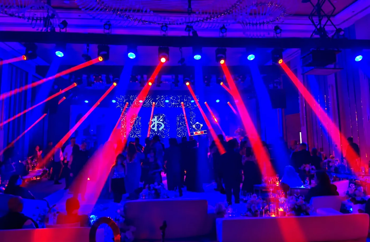 Red lighting beams and blue ambient lighting over a wedding celebration